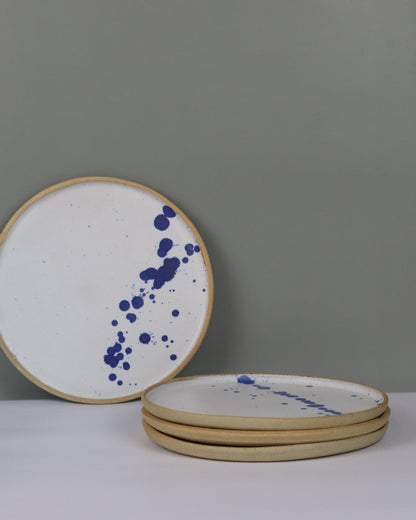 Round ceramic plates with blue speckles on a gray wall.