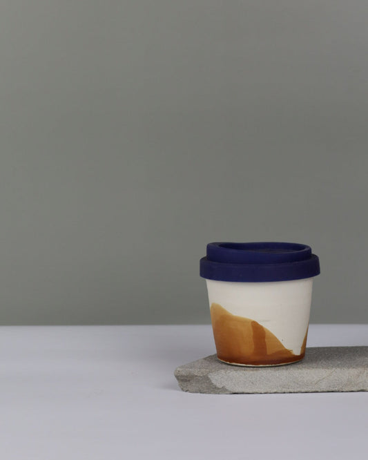 Ceramic mug with a blue lid on a gray background