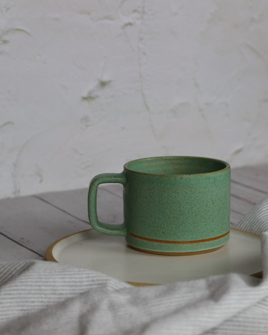 turqouise ceramic mug on top of a white ceramic plate with a napkin