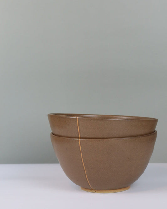 Stack of two brown ramen bowls on a grey background