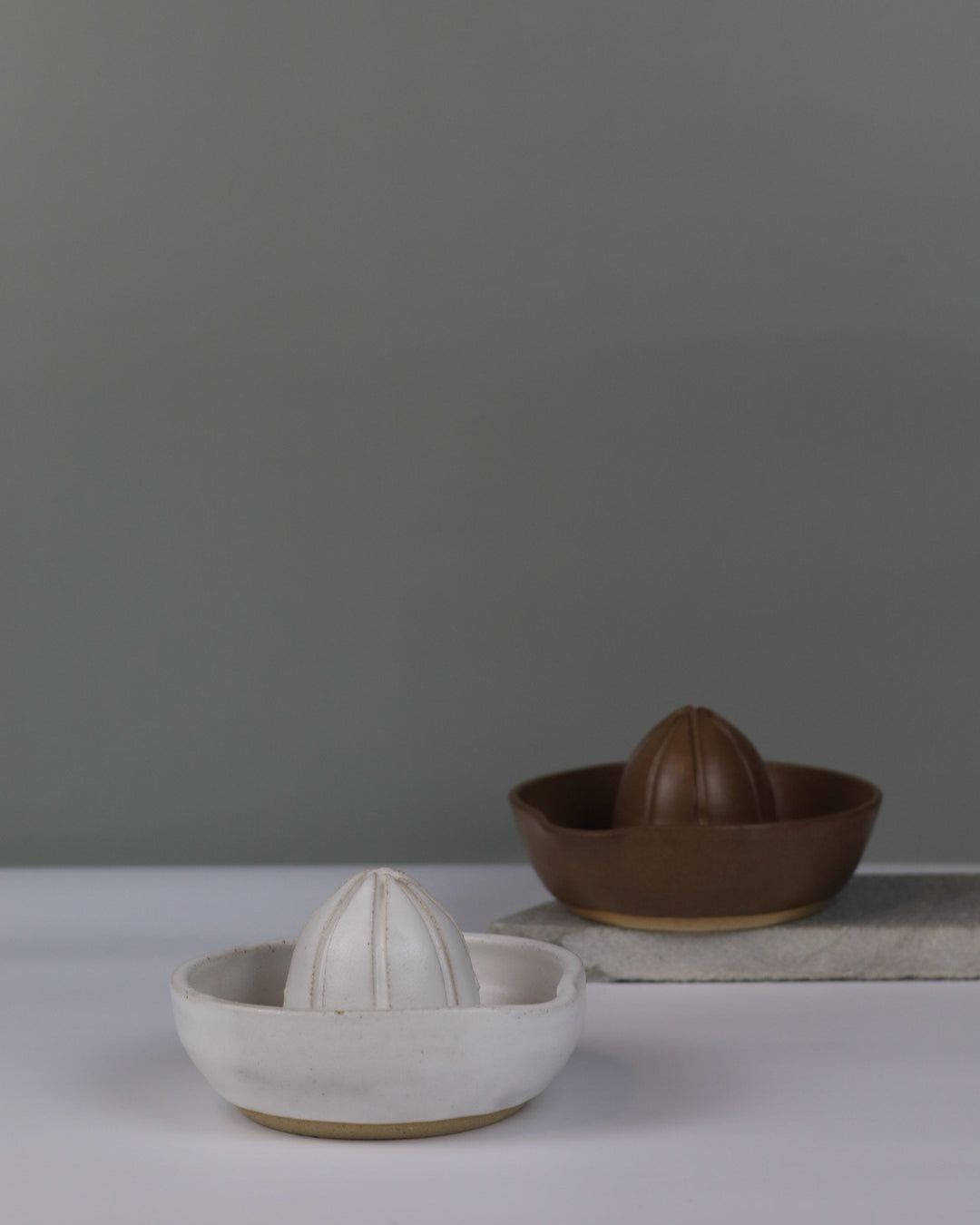 white and cbrown ceramic juicers on a grey background