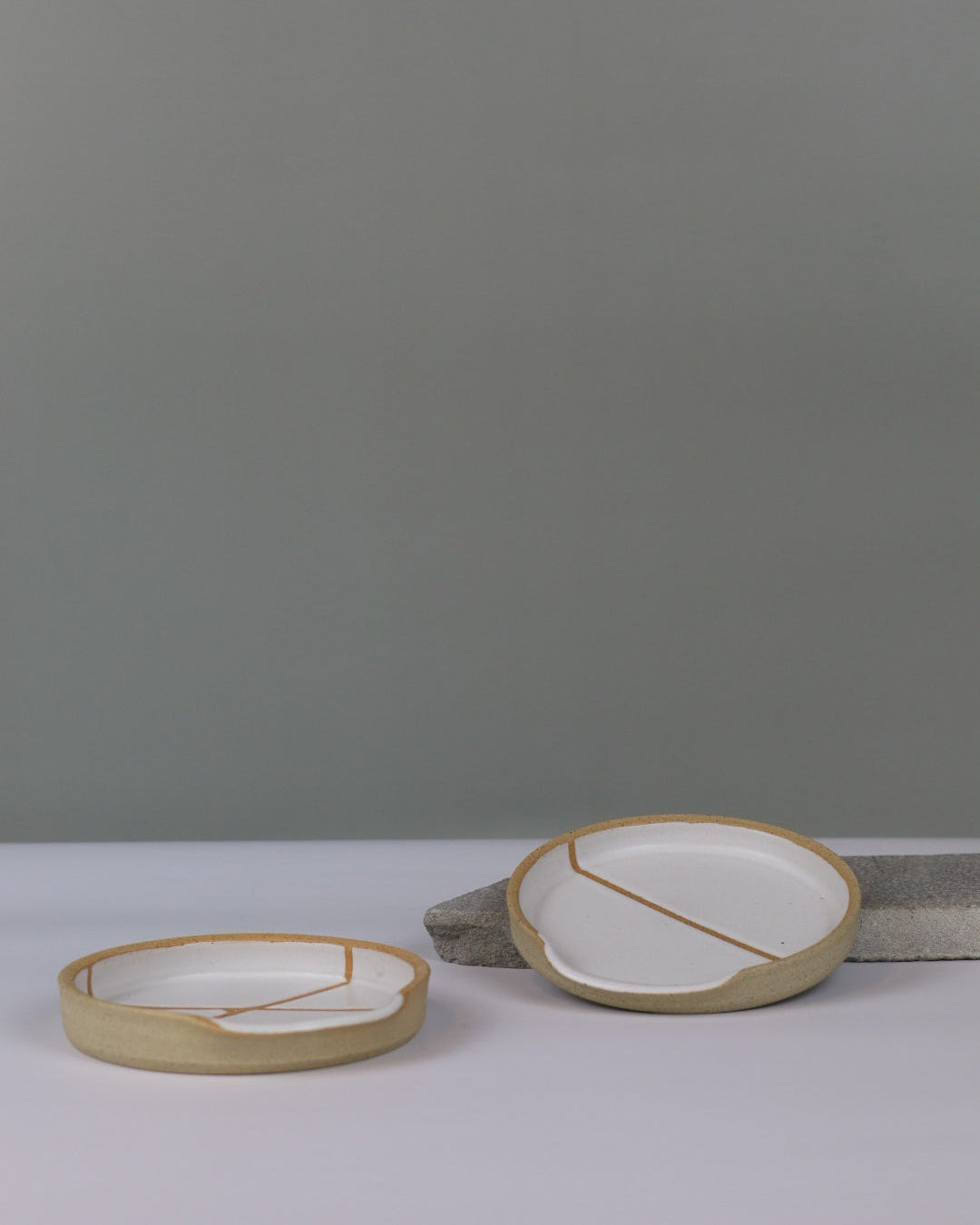 two white ceramic spoon rests on a benchtop